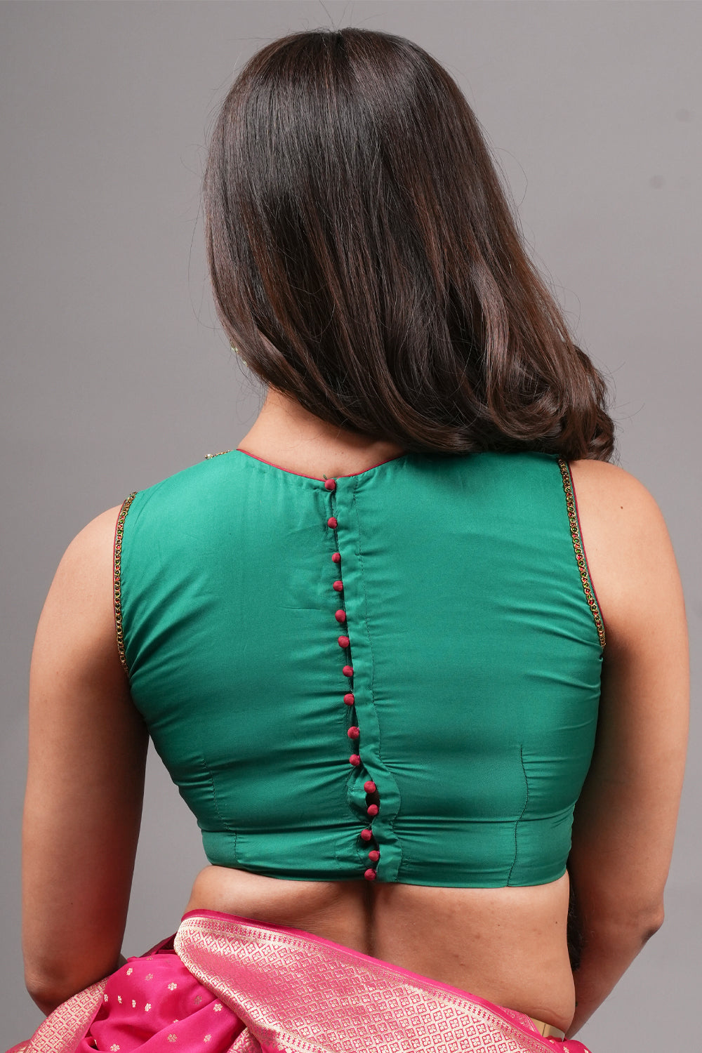 Emerald green silk close neck sleeveless blouse with hand embroidery around neck and armhole.