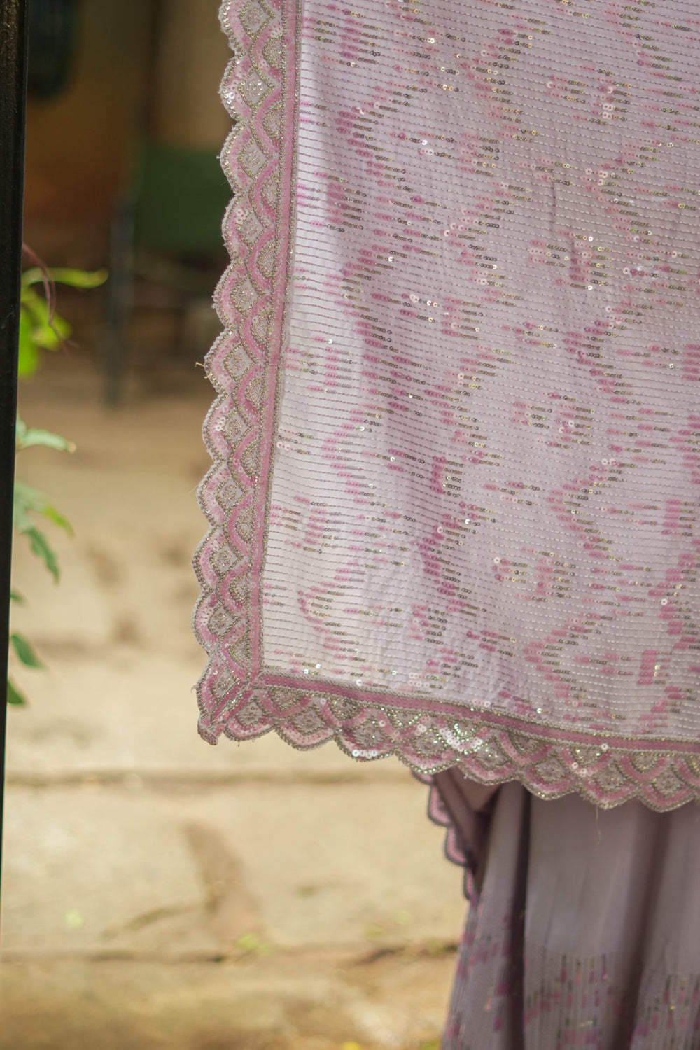Lavender georgette sequin saree with scalloped edging.