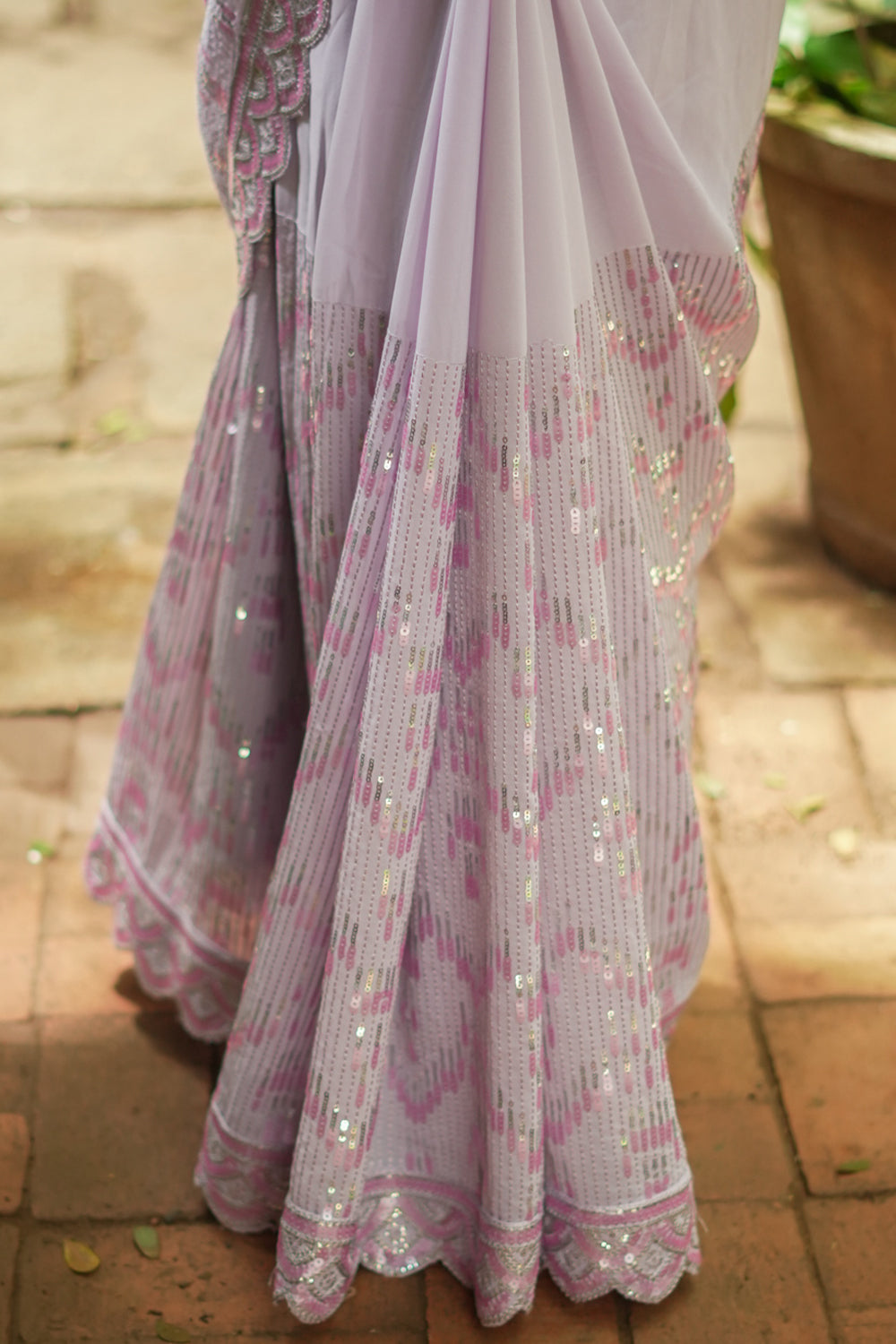 Lavender georgette sequin saree with scalloped edging.