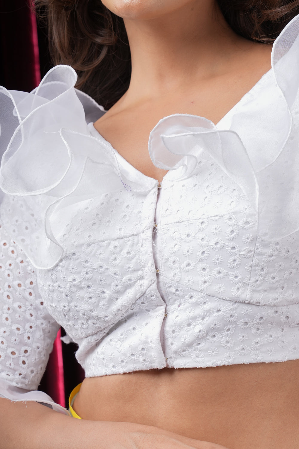 White hakoba V neck blouse with organza ruffles around neck and sleeves.