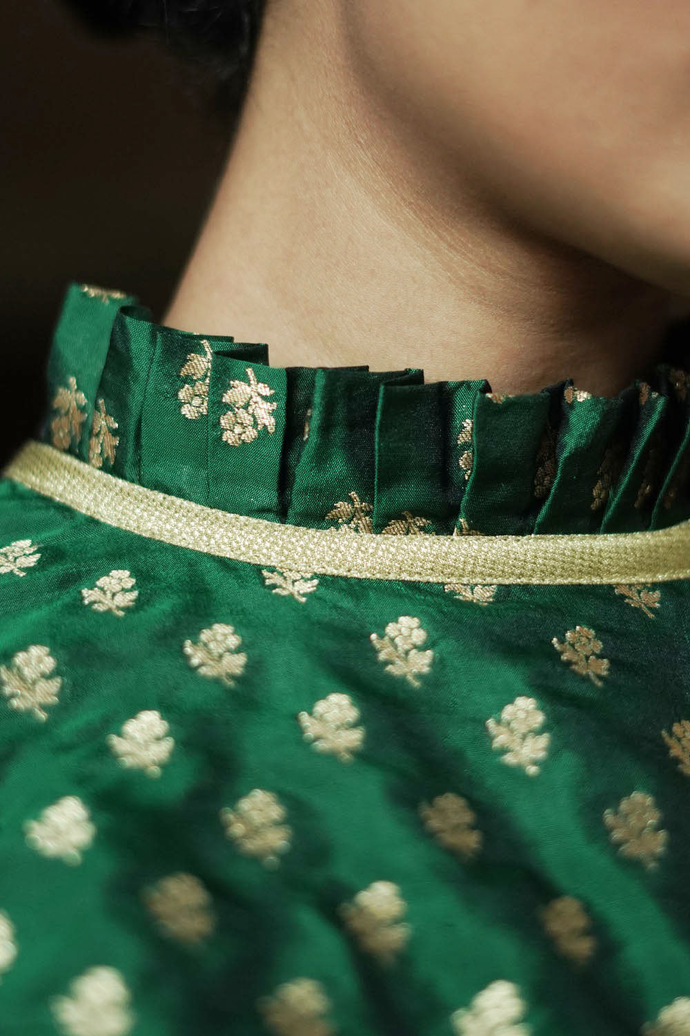 Bottle green banarasi brocade sleeveless blouse with ruffles on neck